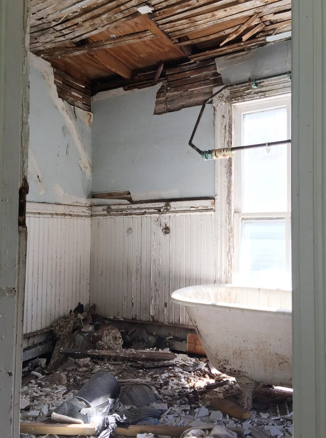 Before Photo Of Beach House Back Bathroom With Crumbling Walls and Clawfoot Tub