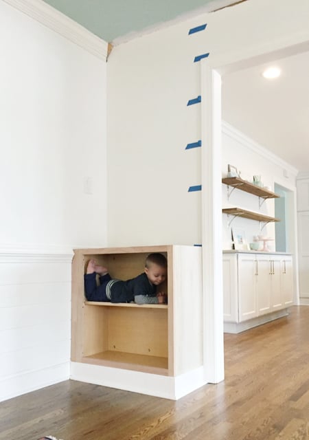 Base cabinet installed for built-in bookshelf with toddler inside