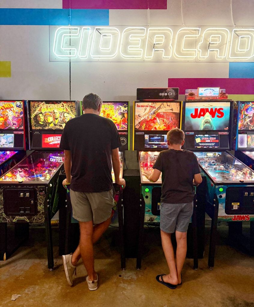 Father and son playing pinball at Cidercade Dallas