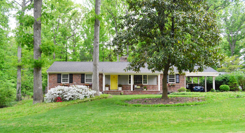 After Photo Of Front Exterior With Trimmed Landscaping And Yellow Painted Door On Brick Ranch