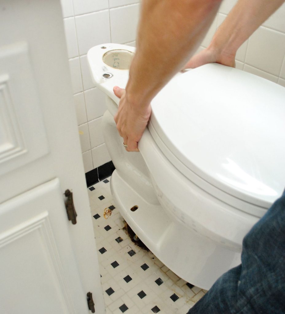 John Placing New Toilet Bowl Onto Ground