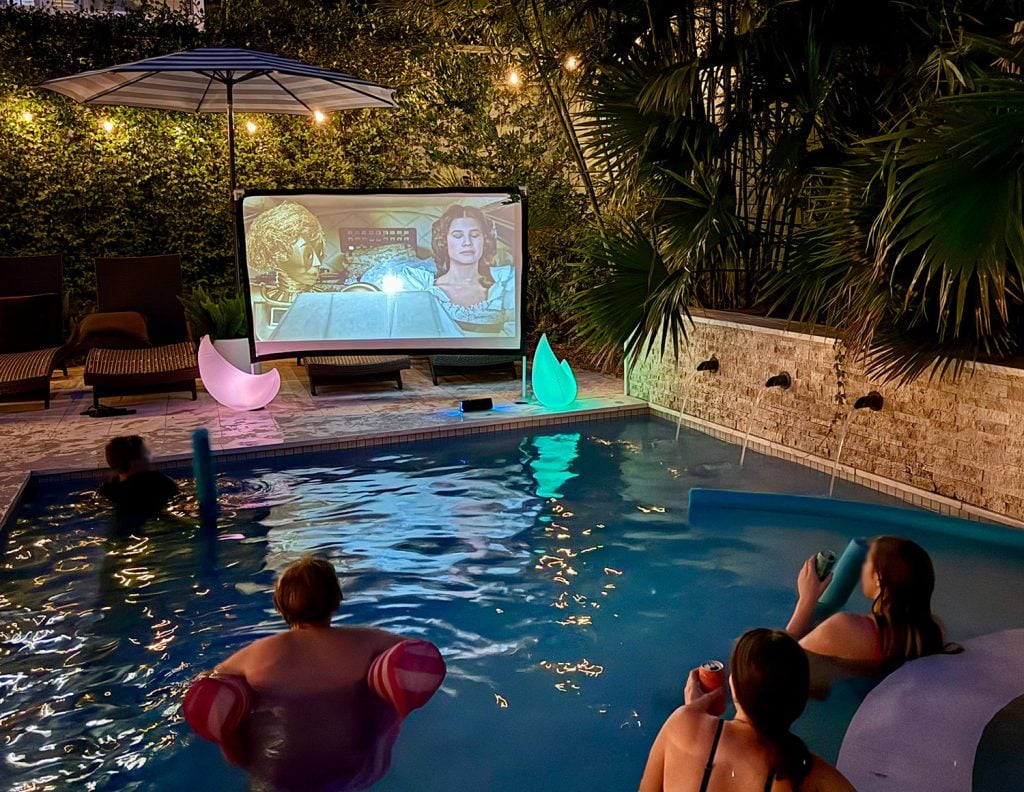 People Watching Movie on Outdoor Screen From Pool