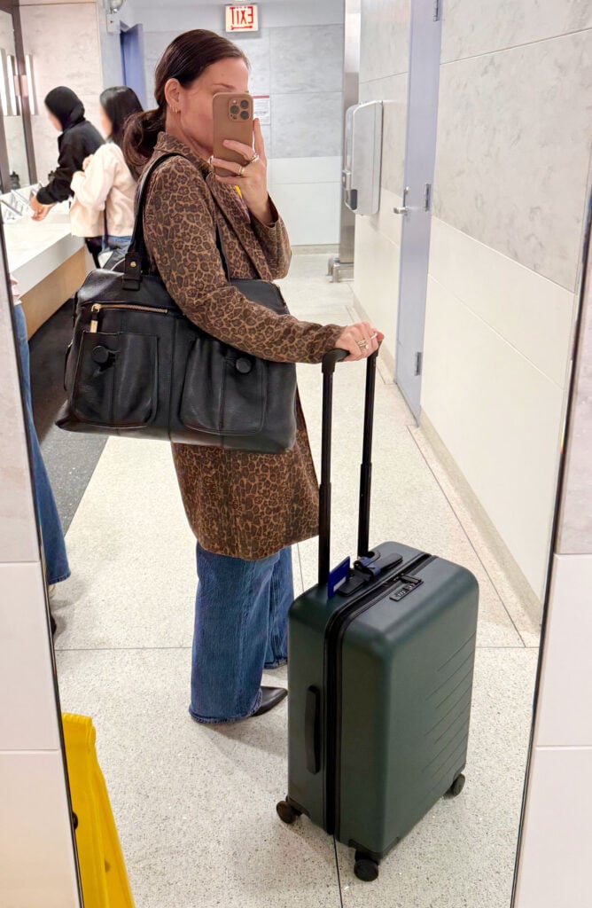 Sherry Selfie In Airport Mirror With Suitcase On Trip To Italy