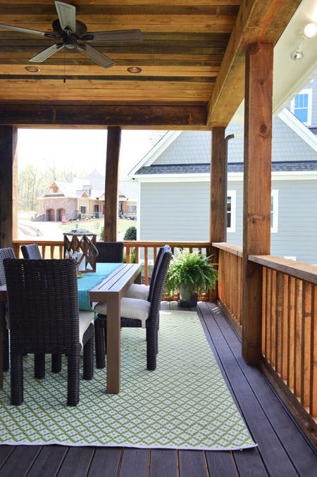 Outdoor Dining Table On Rustic Back Porch With Green Outdoor Rug